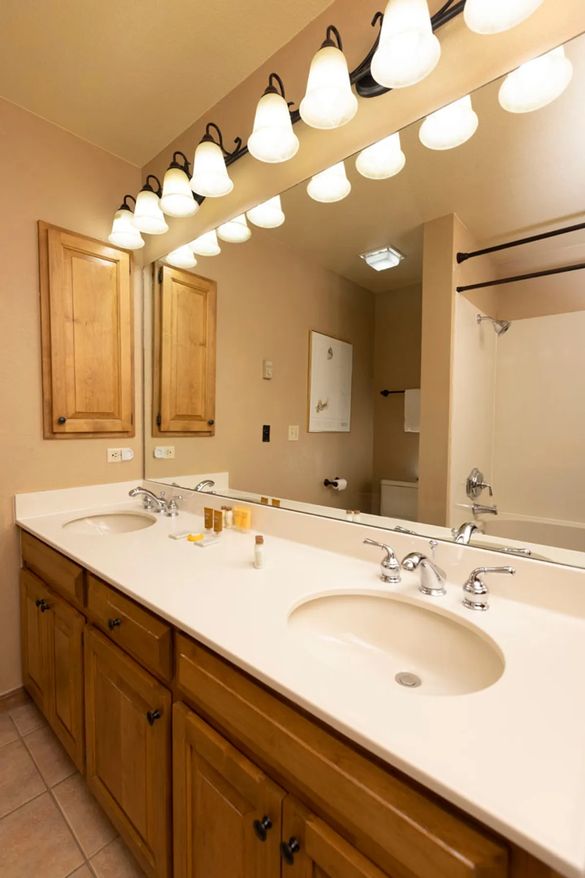 A modern bathroom featuring a spacious double sink vanity, illuminated mirrors, and organized wooden cabinetry. Sleek bathroom accessories and ample counter space make the area both functional and inviting, supporting morning routines or refreshing after outdoor activities.